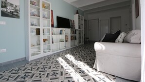 Una sala de estar con piso estampado, un sofá blanco y un mueble con estantes.