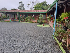 A building with a red roof and green trim, surrounded by gravel and potted plants. - FINCA HOTEL EL VERGEL, VEREDA LOS TANQUES, FILANDIA, QUINDIO. COUNTRY ESTATE (Quindío)