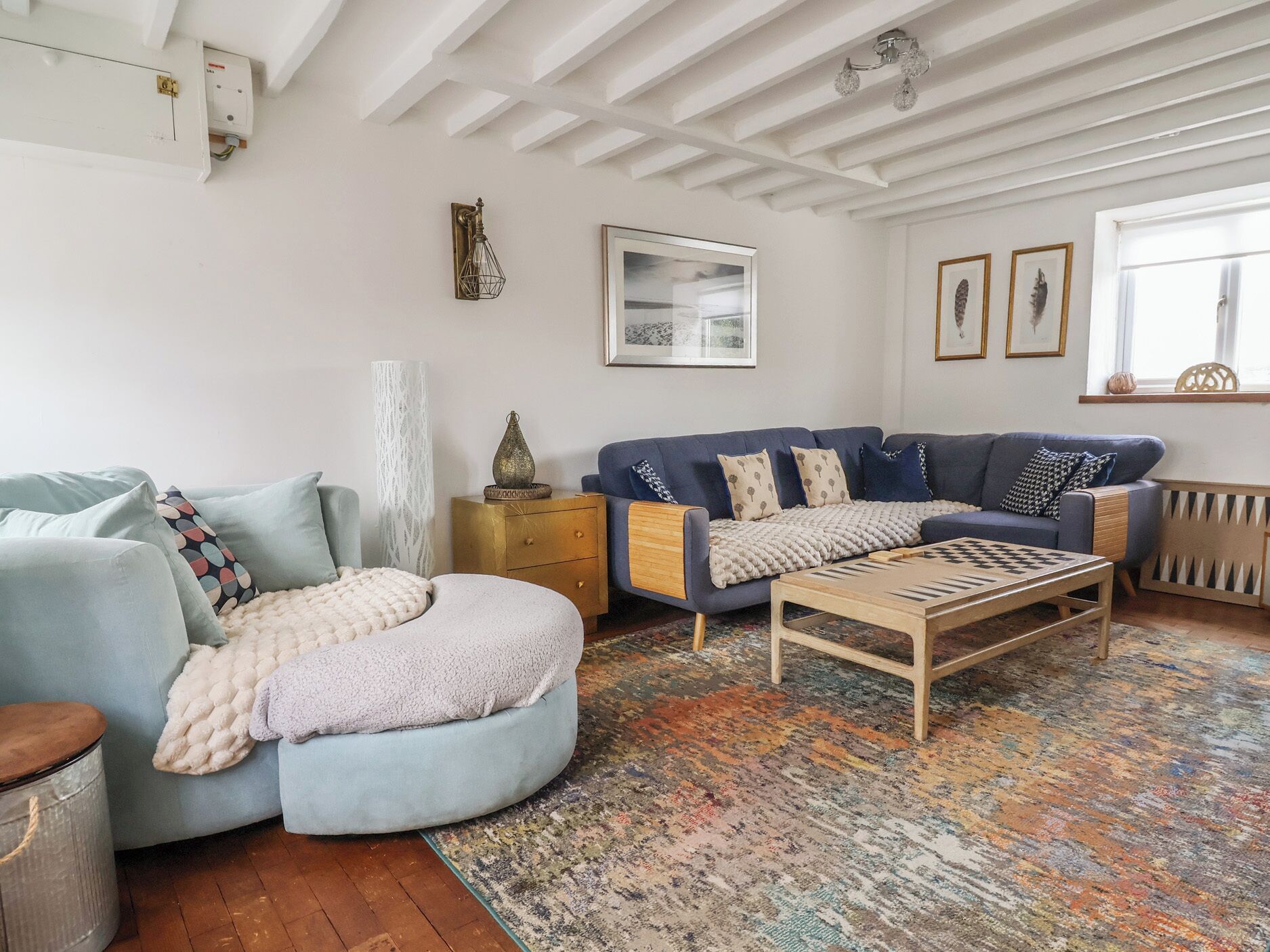 A living room with a blue sofa, a wooden coffee table, a patterned rug, and a white ceiling.
