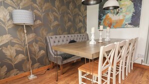 A dining area with a wooden table, white chairs, a tufted bench, and a floor lamp.