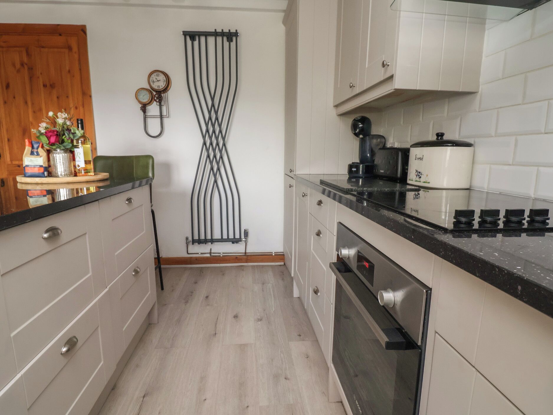 A kitchen with white cabinets, a black countertop, a built-in oven, and a coffee maker.