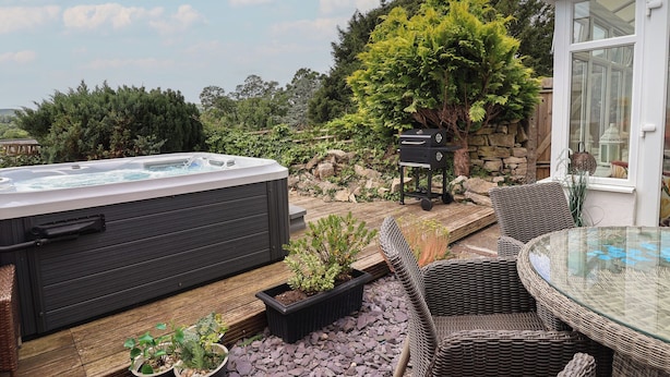 A hot tub, wicker furniture, and a stone wall.