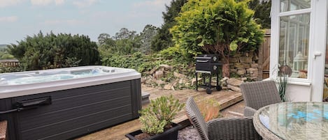 A hot tub, wicker furniture, and a stone wall.