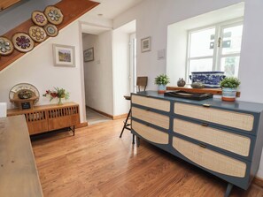 A room with a wooden bench, a blue and gray cabinet, a window with a view, and a staircase with decorative plates. - Tenandeleven Cottage (Denbigh)