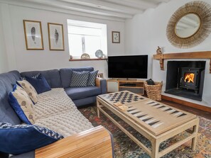 Un salón con sofá, televisión, chimenea y una mesa para jugar al ajedrez.