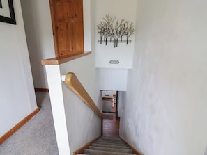A staircase with a wooden handrail, a wall-mounted sign, and a decorative metal piece. - Tenandeleven Cottage (Denbigh)
