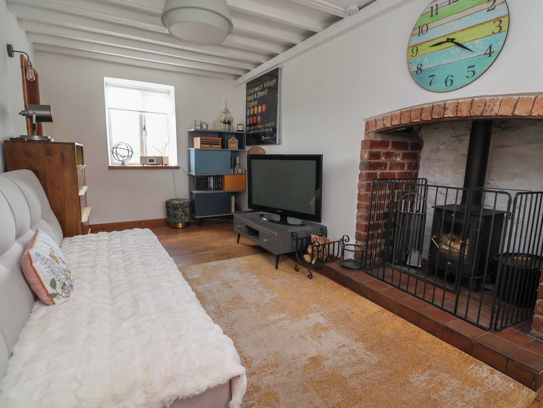 A cozy living room with a fireplace, a television, and a clock on the wall.