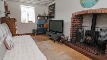 A cozy living room with a fireplace, a television, and a clock on the wall.