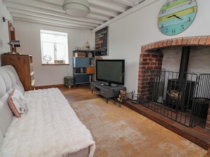 Un salon confortable avec une cheminée, un téléviseur et une horloge au mur.