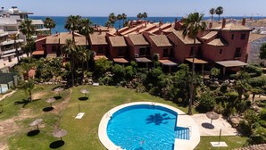 Et hotel med swimmingpool omgivet af palmer og udsigt til havet.