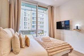 Ein Hotelzimmer mit Bett, Fernseher und Blick auf ein Gebäude.