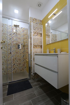 Un bagno con doccia, toilette, lavandino e specchio.