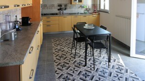 Een keuken met houten balken, een eettafel, stoelen en een vloer met patroon.