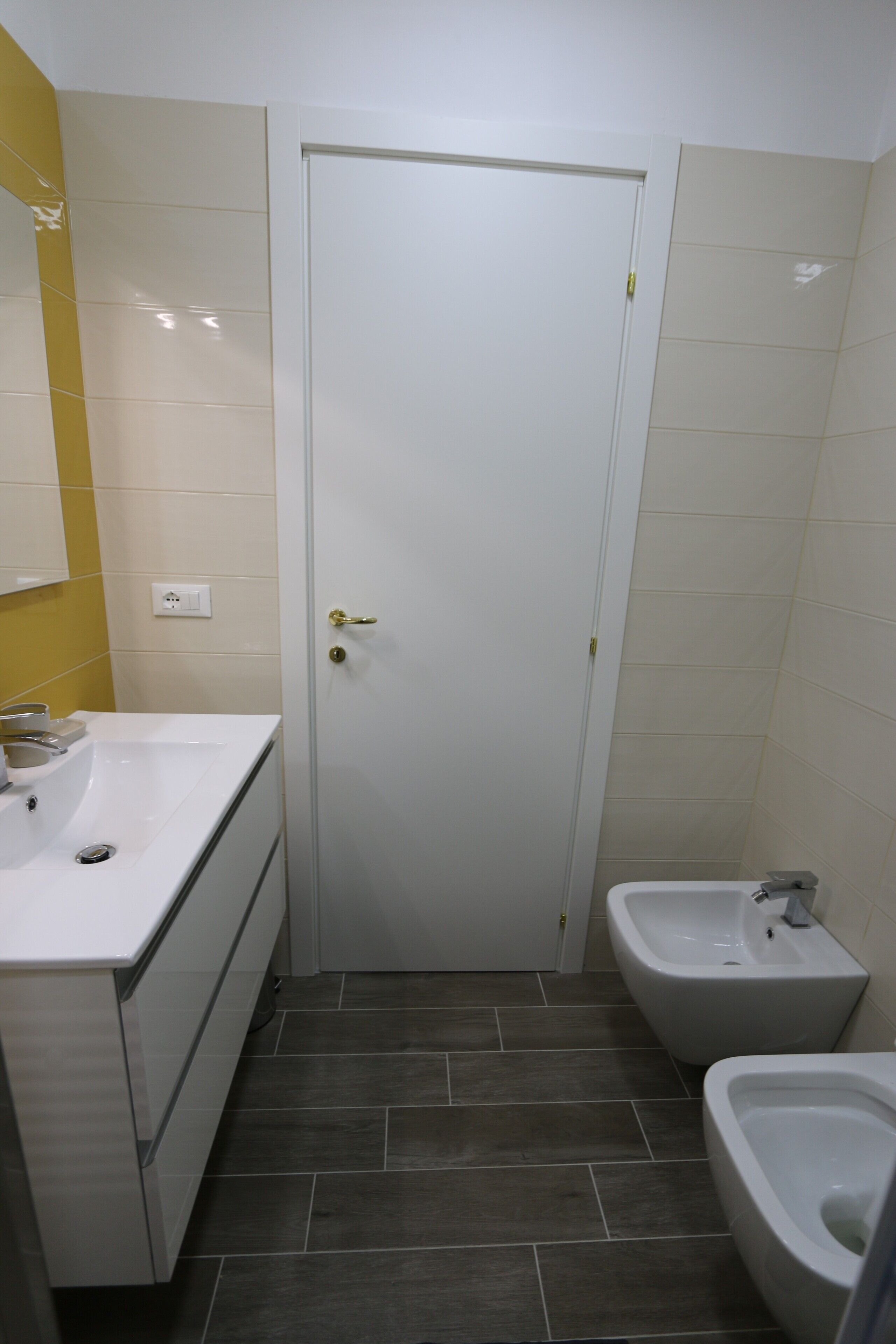 Une salle de bain avec un lavabo blanc, un bidet et une porte.