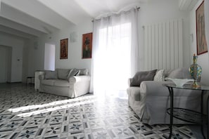 A living room with two sofas, a patterned floor, and a window with curtains.