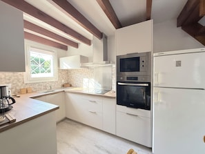 Eine moderne Küche mit weißen Schränken, einem Backofen, einer Mikrowelle und einem Kühlschrank.