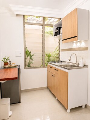A compact kitchen with a window, a sink, and a stove. - Work & Live Private Studio in a Strategic Location (Medellín)