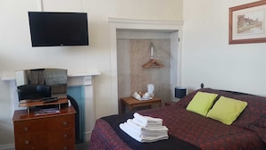 Ein Schlafzimmer mit einem Bett, einem Fernseher, einem Schreibtisch mit Computer und einem Kamin.