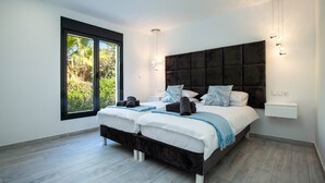 Una camera da letto moderna con due letti, un'ampia finestra e vista sul verde.