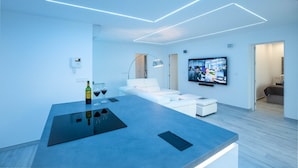 Un soggiorno moderno con un'isola centrale, un televisore a schermo piatto e un divano bianco.