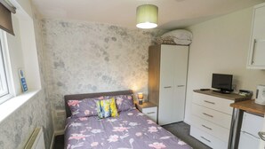 Un dormitorio con cama, escritorio, armario y televisor.