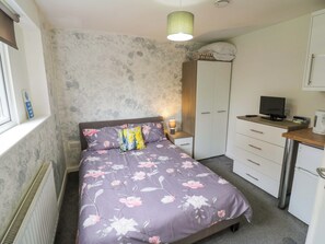 A bedroom with a bed, a desk, a wardrobe, and a television. - Lodge Park (Corby)