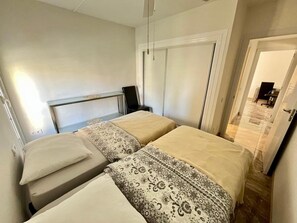 A bedroom with two beds, a bedside table, a chair, and a wardrobe. - A Wonderful Vacation in July in Almerimar (Almerimar)