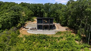 A two-story building with a circular outdoor seating area and a stone pathway leading to it. - Elevated Escapes by Carolina Mornings | Luxury w/PERFECT mountain views near AVL (Candler)