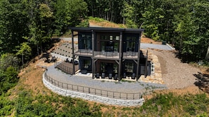 Ein modernes, zweistöckiges Haus mit Steinfundament, Balkon und Terrassenbereich.