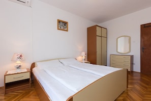 Ein Schlafzimmer mit Bett, Nachttischen, einem Kleiderschrank, einem Spiegel und einem Bild an der Wand.