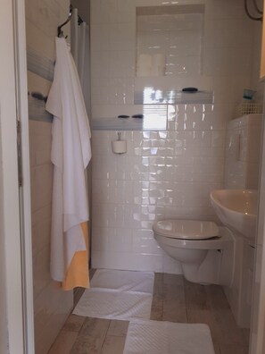 Ein Badezimmer mit Toilette, Waschbecken und Duschbereich.