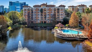 Ein Hotel mit Schwimmbad, Springbrunnen und Spiegelung im Wasser.