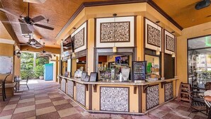 Eine Bar mit kariertem Boden, gefliesten Wänden und Deckenventilatoren.