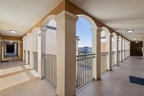 A corridor with columns, railings, and a view of buildings. - 3BR Orlando Stay Near Disney & Universal (Orlando)