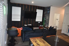 Ein modernes Wohnzimmer mit Flachbildfernseher, einer Couch, einem Couchtisch und einem Essbereich.