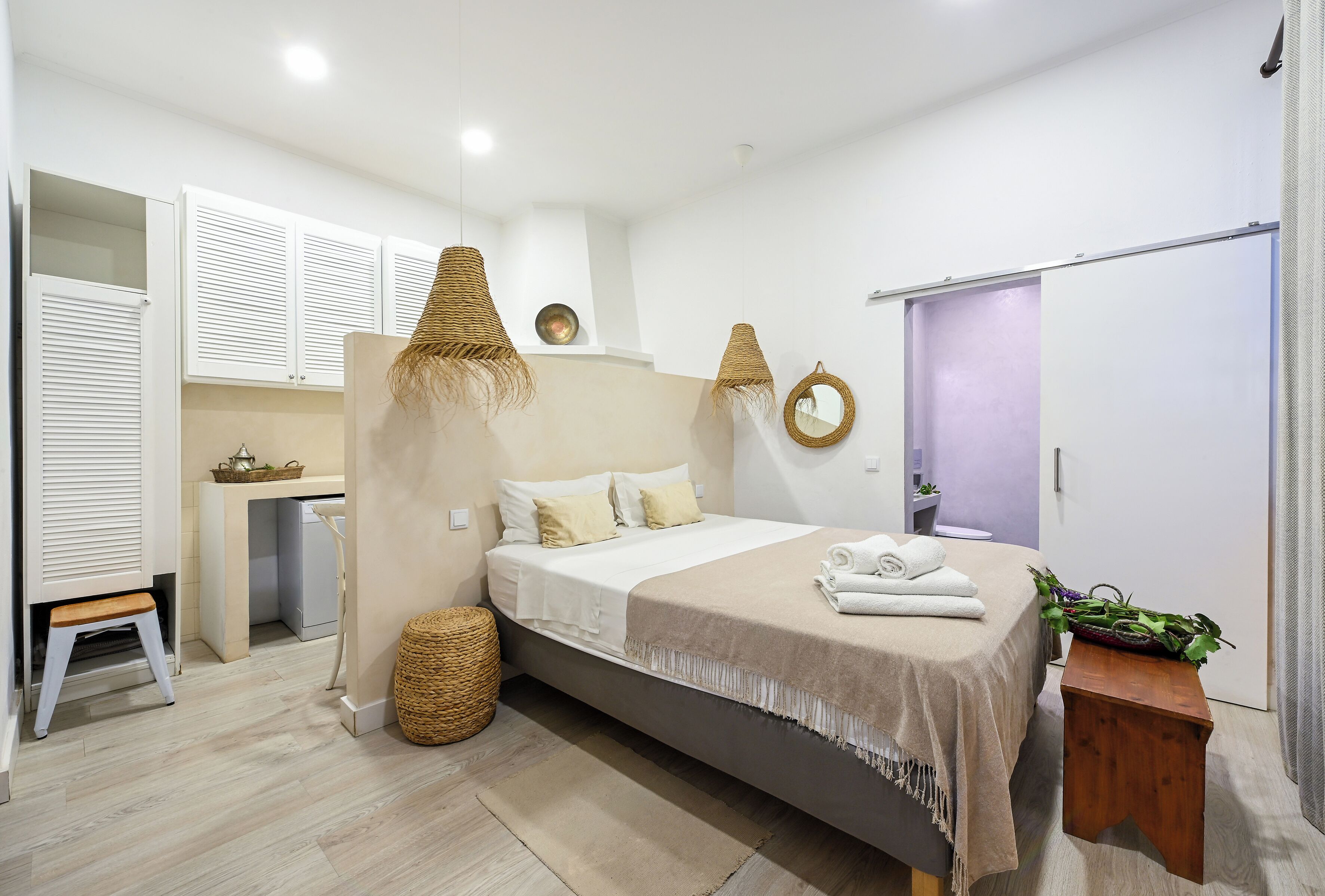 Quarto moderno com cama, mesas de cabeceira, guarda-roupa e um pequeno espaço de trabalho.