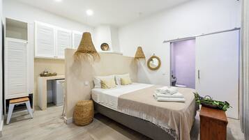 Quarto moderno com cama, mesas de cabeceira, guarda-roupa e um pequeno espaço de trabalho.