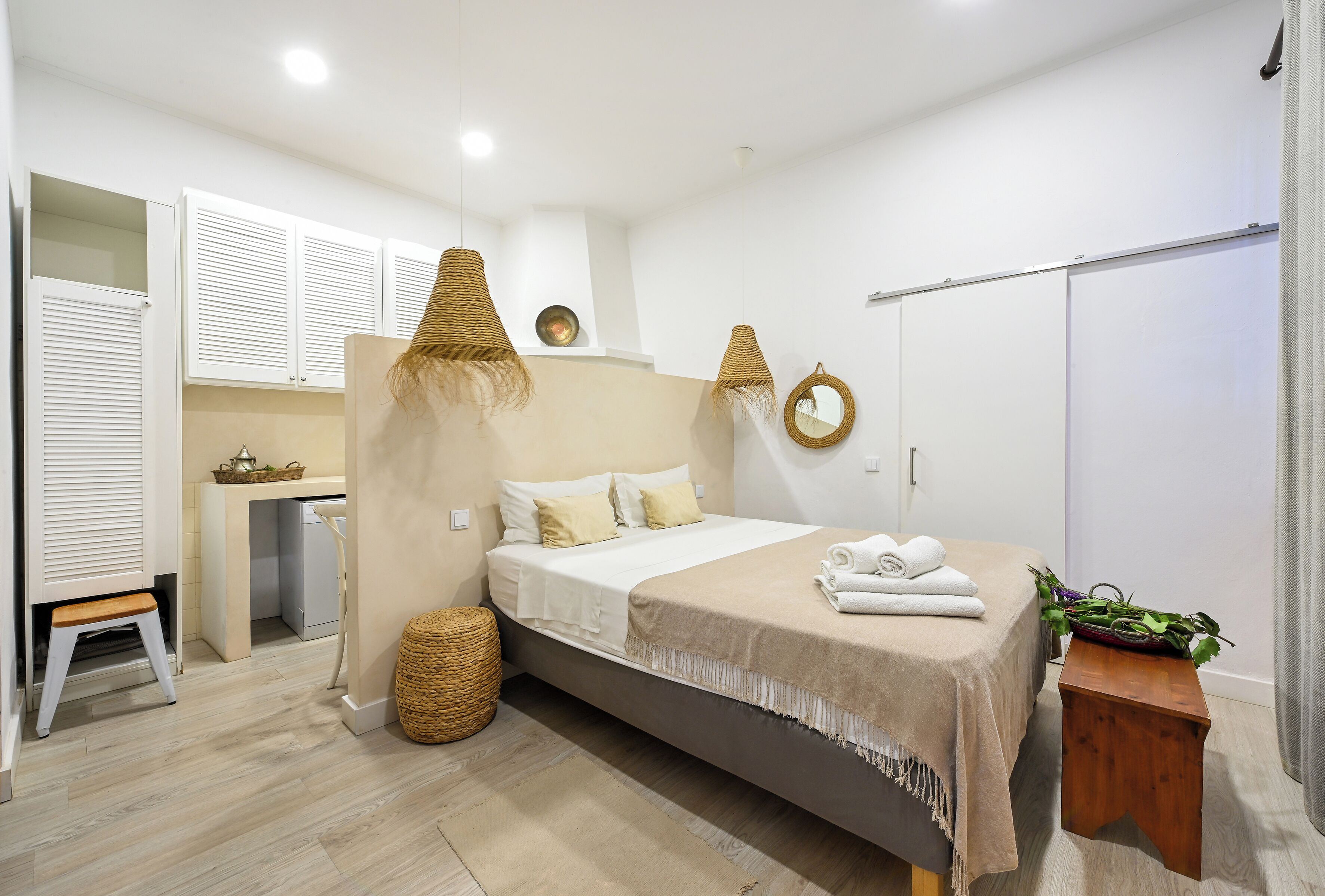 Un dormitorio moderno con cama, mesitas de noche, un armario y una pequeña zona de escritorio.