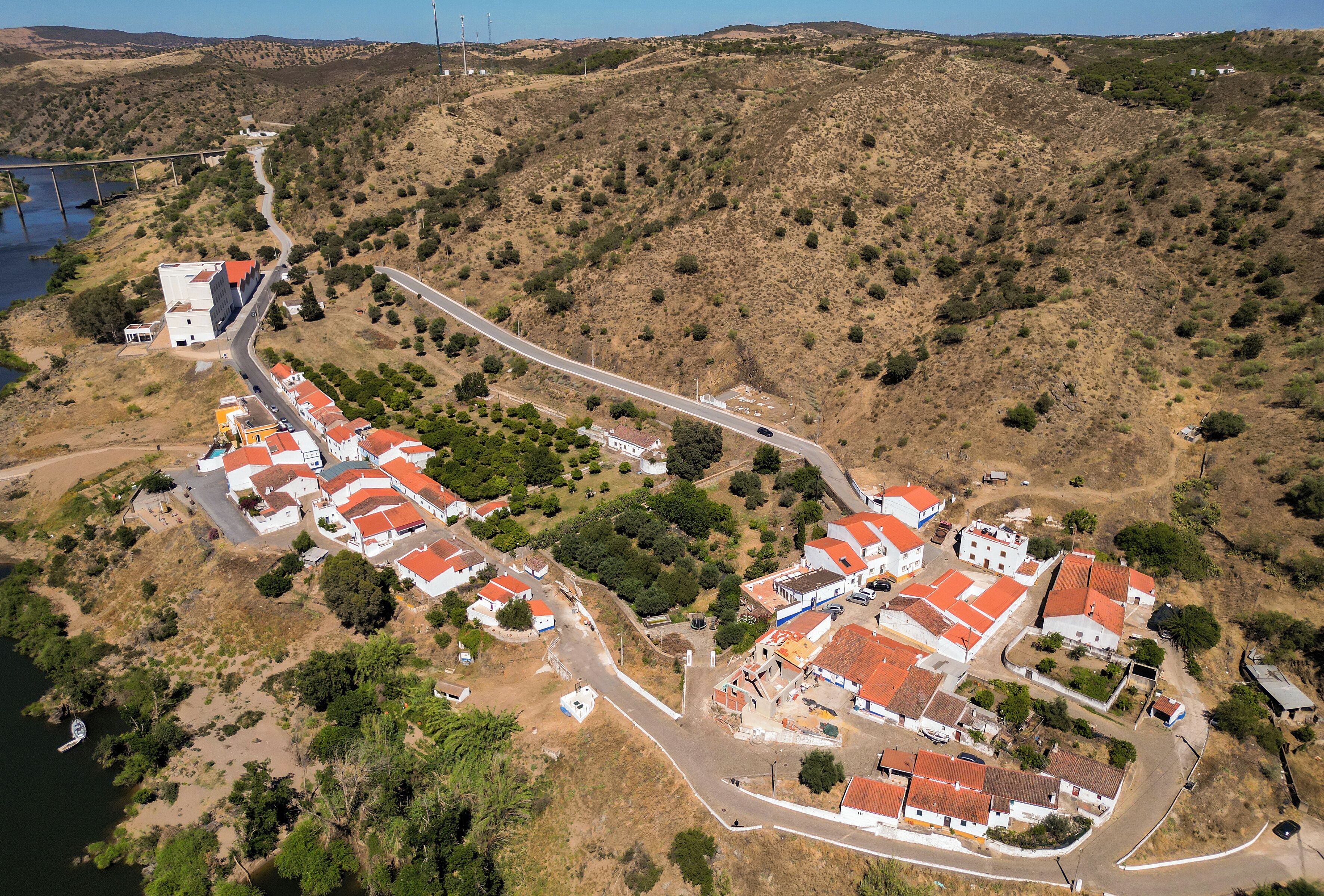 A coastal village with terraced houses, a winding road, and a body of water.