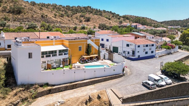 A residential area with houses, a swimming pool, and a road. - Casa Amarela (Mértola)