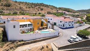 A residential area with houses, a swimming pool, and a road. - Casa Amarela (Mértola)