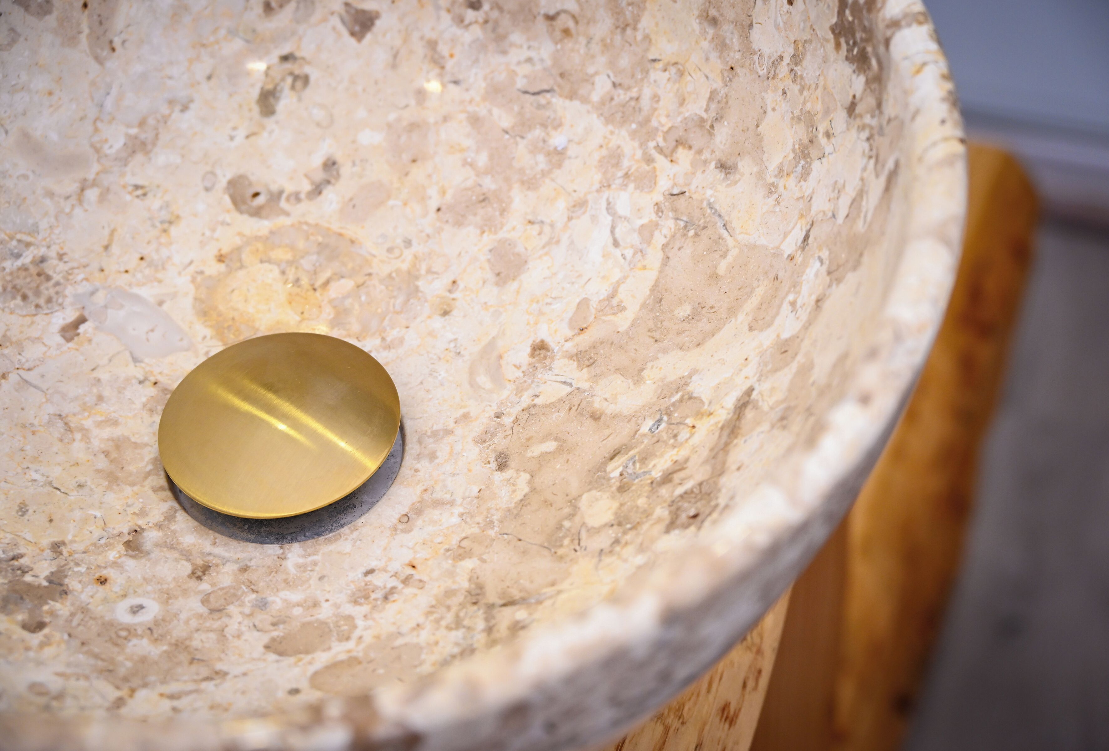 Primer plano de un lavabo de piedra texturizada con tapa de latón.