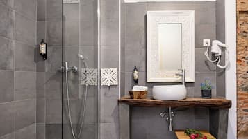 Un baño moderno con cabina de ducha de vidrio, tocador con lavamanos, secador de pelo y un espejo decorativo.
