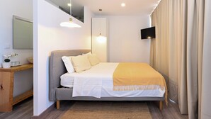 A modern bedroom with a bed, bedside table, mirror, and a TV mounted on the wall. - Casa Amarela (Mértola)