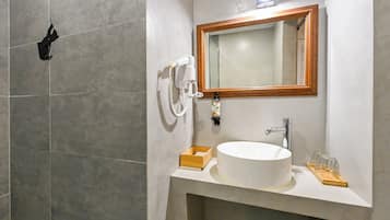 Un baño con un lavamanos blanco, un espejo con marco de madera y un cabezal de ducha manual.