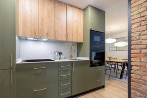 Eine moderne Küche mit Holzausbau, einem Edelstahlspülbecken und einem Essbereich mit Backsteinwand.