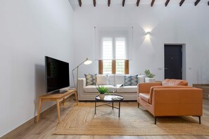 Ein Wohnzimmer mit einer Couch, einem Couchtisch, einem Fernseher und einer Lampe.