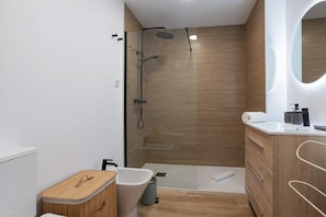Een moderne badkamer met douche, toilet en wastafel.