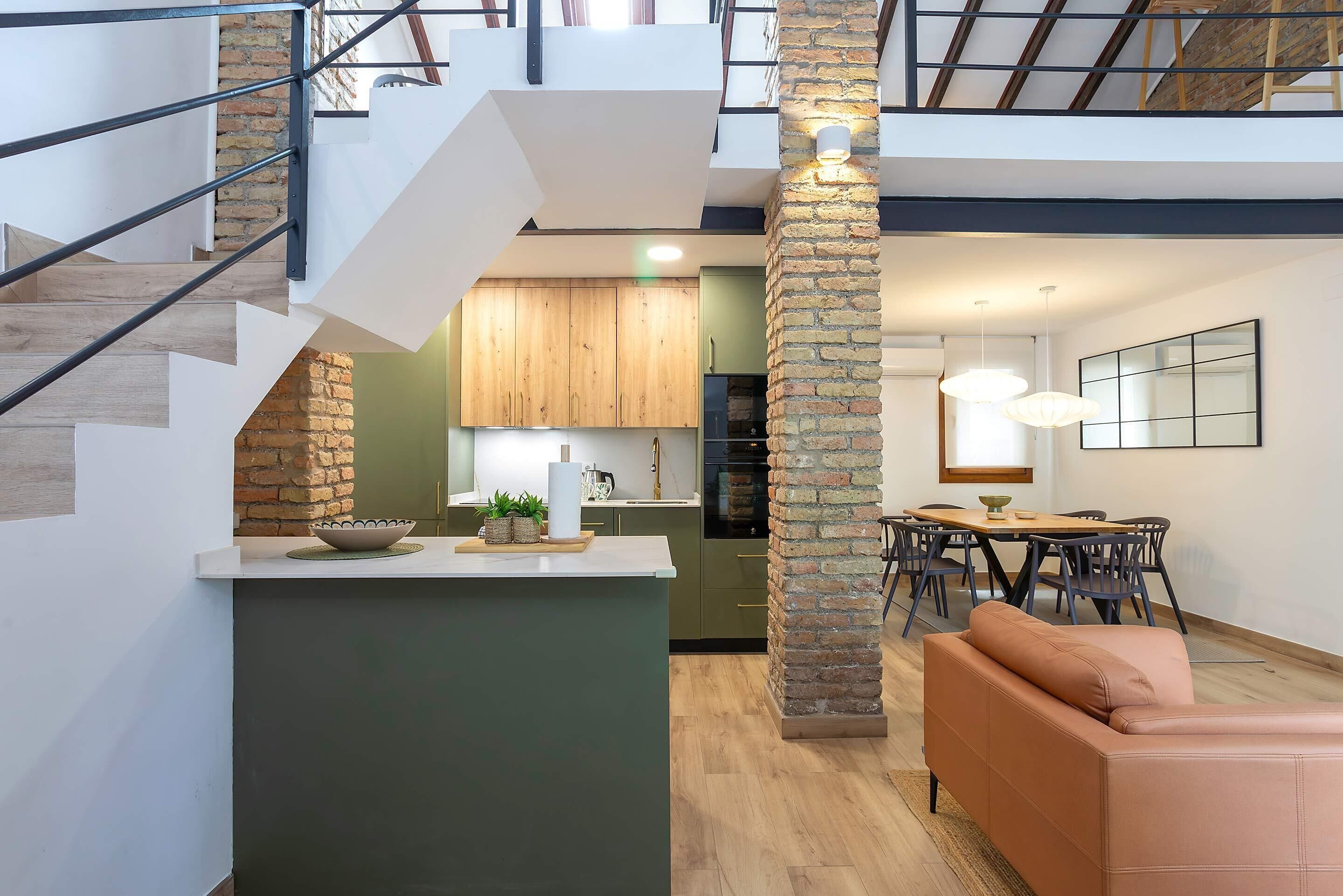 Een modern interieur met een trap, keuken, eethoek en een bank.