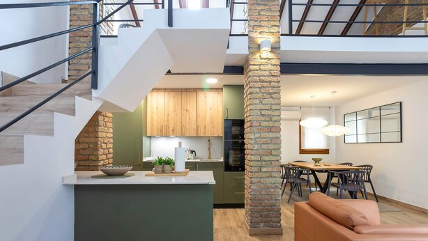 Un interior moderno con una escalera, cocina, comedor y un sofá.